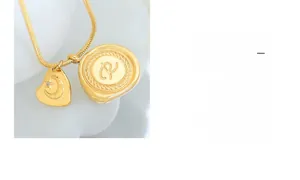 Détail d'une chaîne serpent dorée avec pendentifs cœur et sceau sur fond blanc