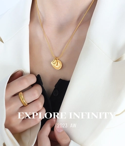Gros plan du collier en titane doré avec pendentifs et bague côtelée assortie élégante