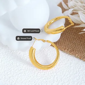 Minimalistische vergoldete Edelstahl-Ohrringe mit poliertem Finish auf weißem Sockel