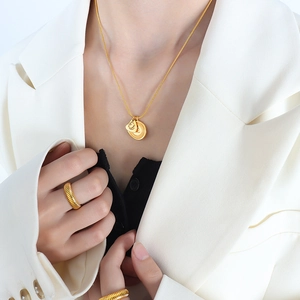 Ensemble collier et bague asymétrique en acier titane plaqué or porté par un mannequin