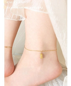 Detailed view of an 18K gold-plated anklet with a rectangular GOLD engraved pendant