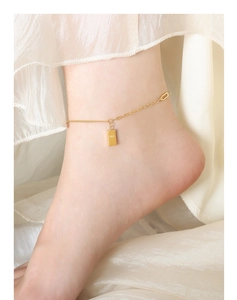 Close-up of gold-plated anklet with rectangular pendant engraved with GOLD on ankle