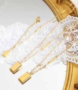 Detail of three gold-plated necklaces with rectangular gold-brick pendants and mixed links
