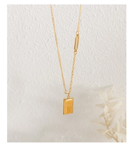 Detail of gold square pendant engraved with GOLD on minimalist asymmetric chain