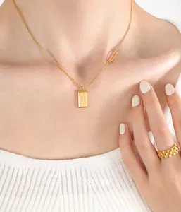 Close-up of gold pendant necklace with square gold bar and matching chain ring