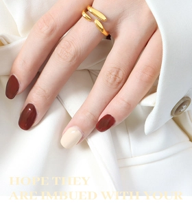 Détail d'une bague dorée irrégulière à double couche sur un doigt et blazer blanc