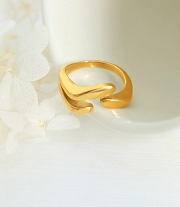 Détail d'une bague ouverte irrégulière en or mat avec un design structurel profilé