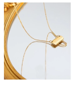 Detail of 18K gold plated square pendant with engraved letter on a vintage mirror