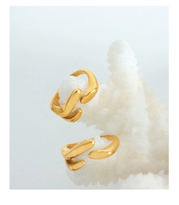 Présentation artistique de bagues dorées fluides sur corail blanc et fond bleu doux