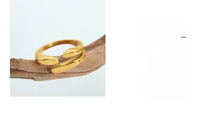 Détail d'une bague ouverte dorée irrégulière présentée sur un support en bois naturel