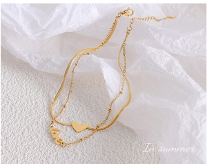 Détail d'une chevillère dorée à double couche avec pendentif cœur et mot love