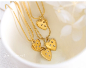 Detail view of heart pendant with three zircons on a delicate gold snake chain