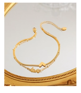 Détail de la chevillère dorée à double rangée avec pendentif cœur et lettrage love