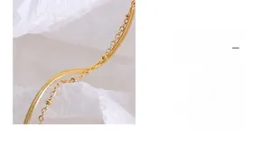 Détail macro d'une chevillère double couche dorée avec chaîne serpent et perles décoratives
