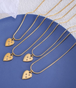 Detail of 18K gold-plated snake chains with zircon heart pendants on a blue tray
