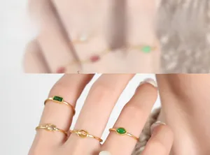 Detail of four gold-plated titanium rings set with emerald and clear zircon stones