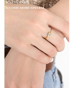Detail of a slim gold-plated titanium ring with an oval glass stone on a hand