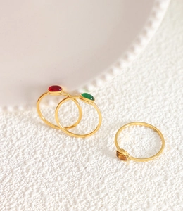Detailed close-up of three gold-plated titanium rings with red, green and amber stones
