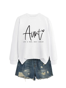 Flat lay of white crewneck sweatshirt with 'Aunt Like A Mom' print and ripped denim shorts