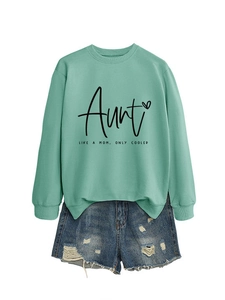 Close-up of mint green crewneck sweatshirt with Aunt text and distressed denim shorts