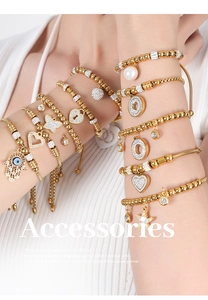 Close-up of stacked gold-plated beaded bracelets with Fatima hand and evil eye charms