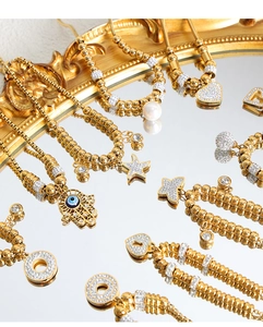 Close-up of 18K gold plated charms including Hamsa, star, and heart on a vintage mirror