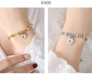 Detailed close-up of 18K gold and silver beaded bracelets with crystal heart lock pendants