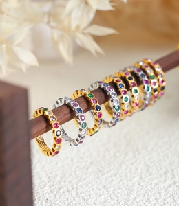 Detail view of colorful eternity rings with gold and silver bands on wooden stand