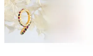 Detail view of gold-plated ring inlaid with colorful crystals in red, green, and blue
