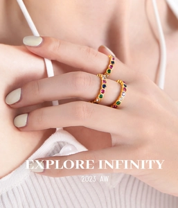 Detail of stacked gold-plated titanium rings featuring colorful inlaid cubic zirconia stones