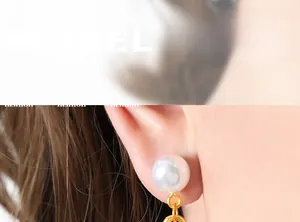 Close-up of elegant gold drop earring with round pearl worn on a model's ear