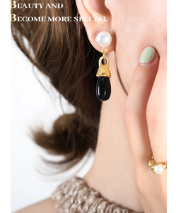 Close-up of vintage pearl earrings and matching ring set on a model with golden accents