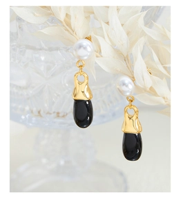 Macro view of vintage-style drop earrings with white pearls and black teardrop charms