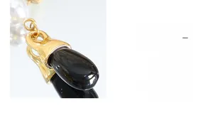 Macro detail of elegant teardrop black gemstone and white pearl earring with gold link