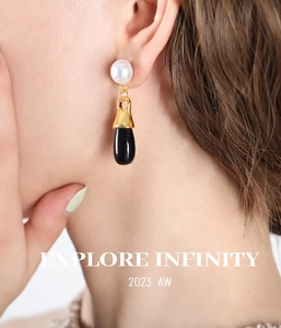 Close-up of vintage style pearl and black teardrop pendant earrings on a model