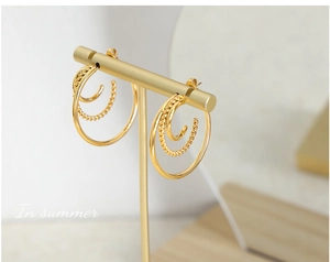 Close-up of golden triple-layered C-shape earrings with twisted rope detail on display