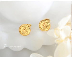 Detail of gold titanium steel studs featuring embossed celestial moon and stars patterns