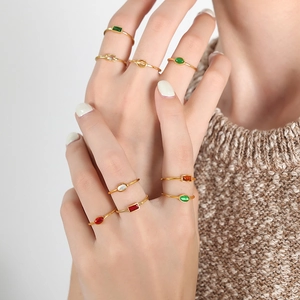 Minimalist gold-plated titanium rings set with colorful gemstone accents on a model