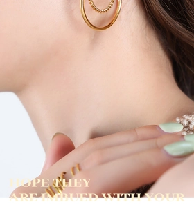 Detail of 18K gold-plated C-shaped earrings and minimalist rings on female model