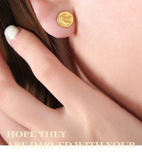 Close-up of titanium steel gold-plated moon and stars embossed earring on model