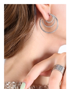 Detail of silver C-shaped earrings and multi-layer ring with twisted rope texture