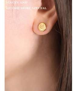 Detailed close-up of golden titanium steel stud earrings with embossed moon and star motifs