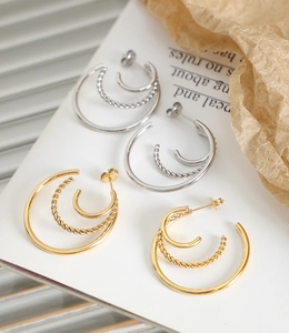 Detail view of 18K gold and silver plated C-shape triple hoop earrings with twisted metal texture