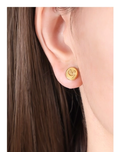 Detail view of a vintage gold titanium steel earring with embossed star and moon pattern