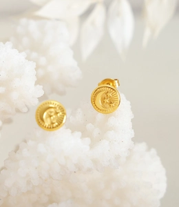 Macro shot of gold-plated celestial earrings with embossed crescent moon and star motifs