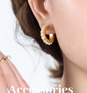 Close-up of golden C-shaped pearl earrings and ring set with vintage hollowed textures