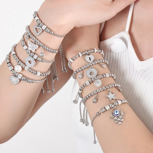 Silver beaded bracelet set with devil eye, heart, and butterfly charms on model's wrist