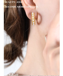 Macro detail of French vintage style C-shaped gold earrings with embedded pearls