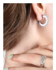Detailed view of silver C-shaped earrings with faux pearls and hollow chain ring on model
