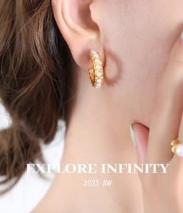 Close-up of elegant gold C-shaped earrings with pearls worn by a model in soft light